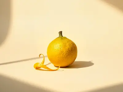 Whole bergamot with granular yellow skin, a ribbon of peel beside it