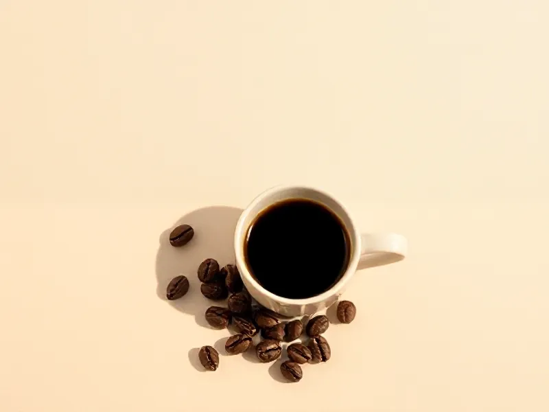 Cup of black coffee surrounded by roasted beans