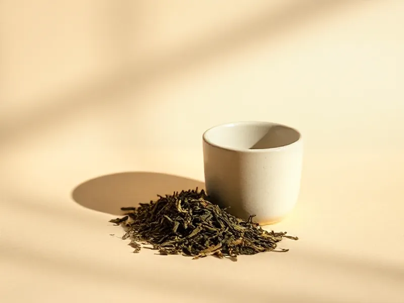 Green tea leaves in front of a cup